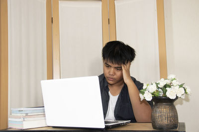 Young woman using mobile phone while sitting on table