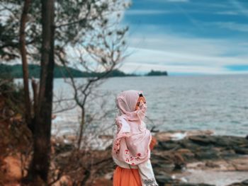 Woman standing at beach against sky