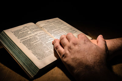 Close-up of hands holding bible in darkroom