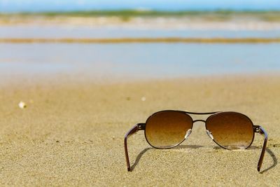 Close-up of sunglasses on sandy beach