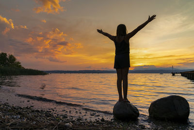 Man standing on beach against sky during sunset