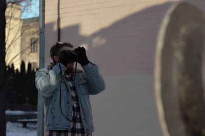 Man photographing through camera against building