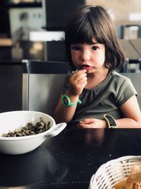 Portrait of cute girl eating food while sitting at home