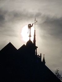 Low angle view of silhouette sculpture against building