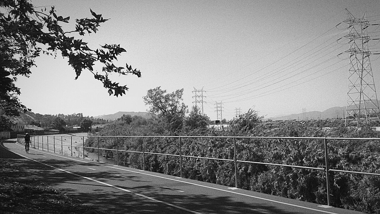 clear sky, tree, railing, copy space, tranquility, tranquil scene, landscape, fence, nature, road, transportation, scenics, sky, beauty in nature, outdoors, mountain, growth, field, day, blue