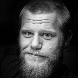 Close-up portrait of man smiling against black background