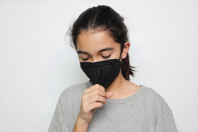 Portrait of woman covering face against white background