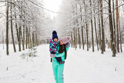 Rear view of woman walking on snow covered field