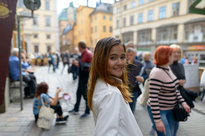 Portrait of woman standing on busy street in city