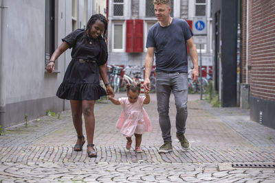 Interracial couple teaching their toddler to walk