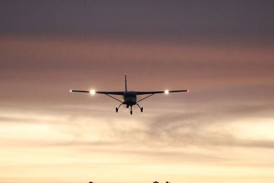 Low angle view of airplane against sky at sunset