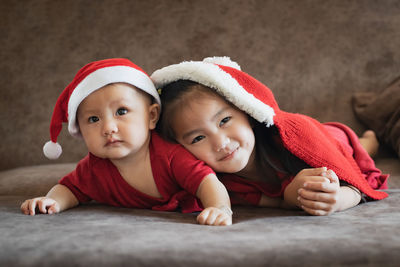 Cute siblings lying on bed at home