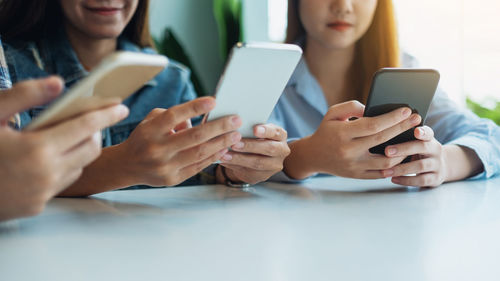 Cropped hands of woman using mobile phone on table