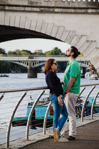 Friends standing on bridge over water