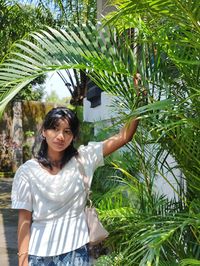 Portrait of young woman standing against plants