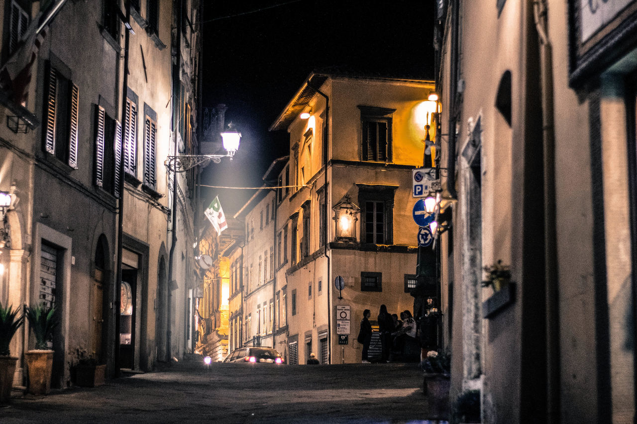 NARROW STREET AMIDST BUILDINGS IN CITY AT NIGHT