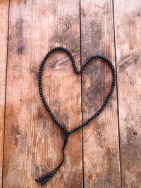 High angle view of heart shape made with bracelet on wooden table