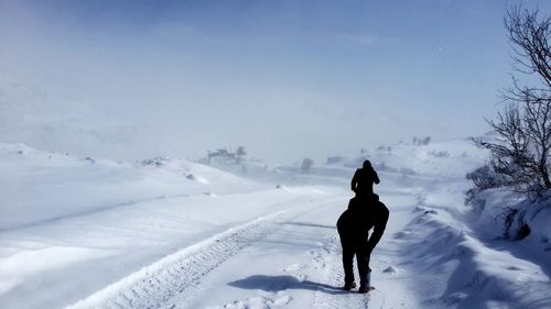 Rear view of person on snowcapped field against sky