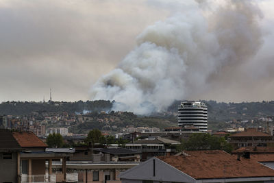 Smoke emitting from roof against buildings in city