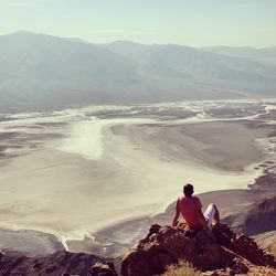 Rear view of man sitting on rock