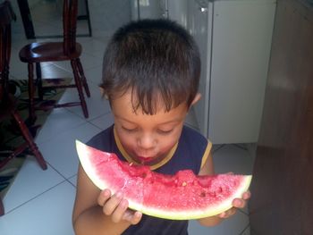 High angle view of boy eating watermelon slice at home