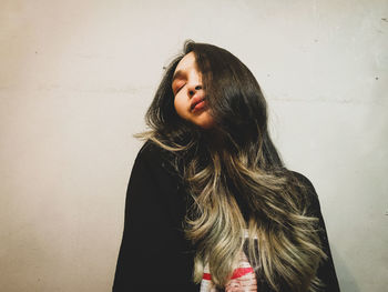 Young woman looking away against wall