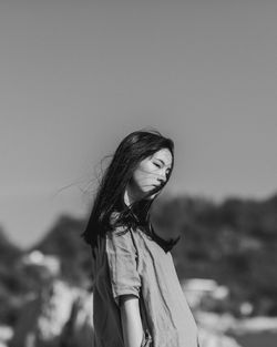 Young woman standing at beach against sky