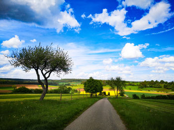 Scenic view of road amidst field against sky