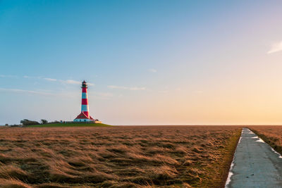 Lighthouse by sea against clear sky