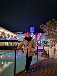 Full length of woman standing against illuminated building at night