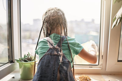 Rear view of woman with umbrella seen through window