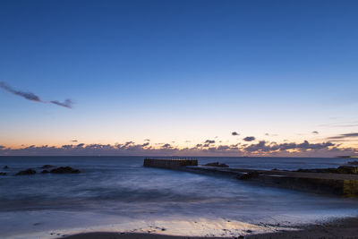 Scenic view of beach against clear sky at sunset