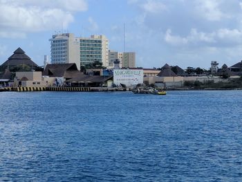 Sea by cityscape against sky