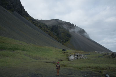 Woman standing on landscape against cloudy sky