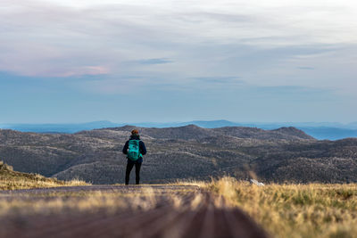 Rear view of man standing on mountain against sky