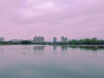 Scenic view of lake against sky in city
