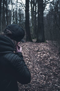 Rear view of man photographing in forest