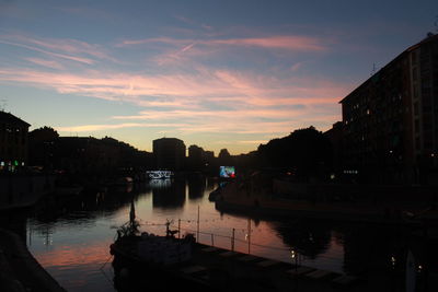 Silhouette boats moored in city against sky during sunset