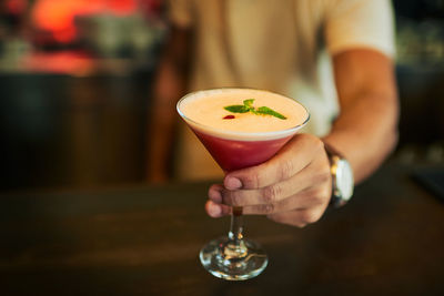 Midsection of woman holding drink on table