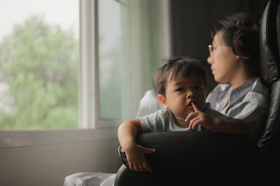 Mother and daughter sitting on window