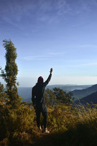 Rear view of man standing on mountain against sky