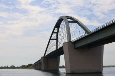 Low angle view of bridge over river against sky