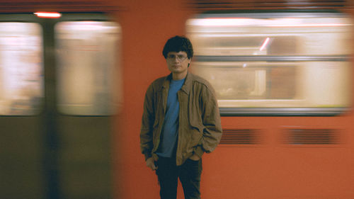 Portrait of young man standing by train