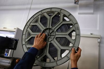 Cropped hands of male mechanic repairing with film projector