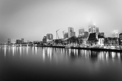 Buildings by river against sky in city