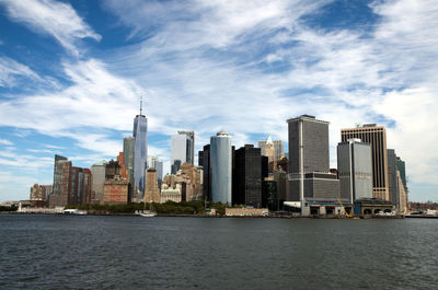 Sea by modern buildings in city against sky