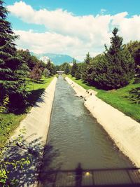 Empty footpath by canal against sky