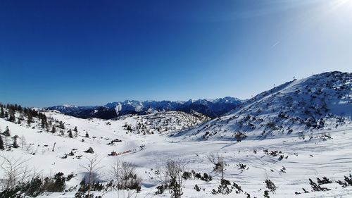 Scenic view of snow covered mountains against clear blue sky