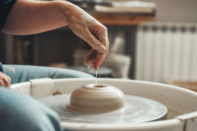 The hands of ceramist create pottery on a pottery wheel