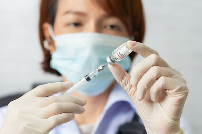 Doctor wearing mask preparing syringe